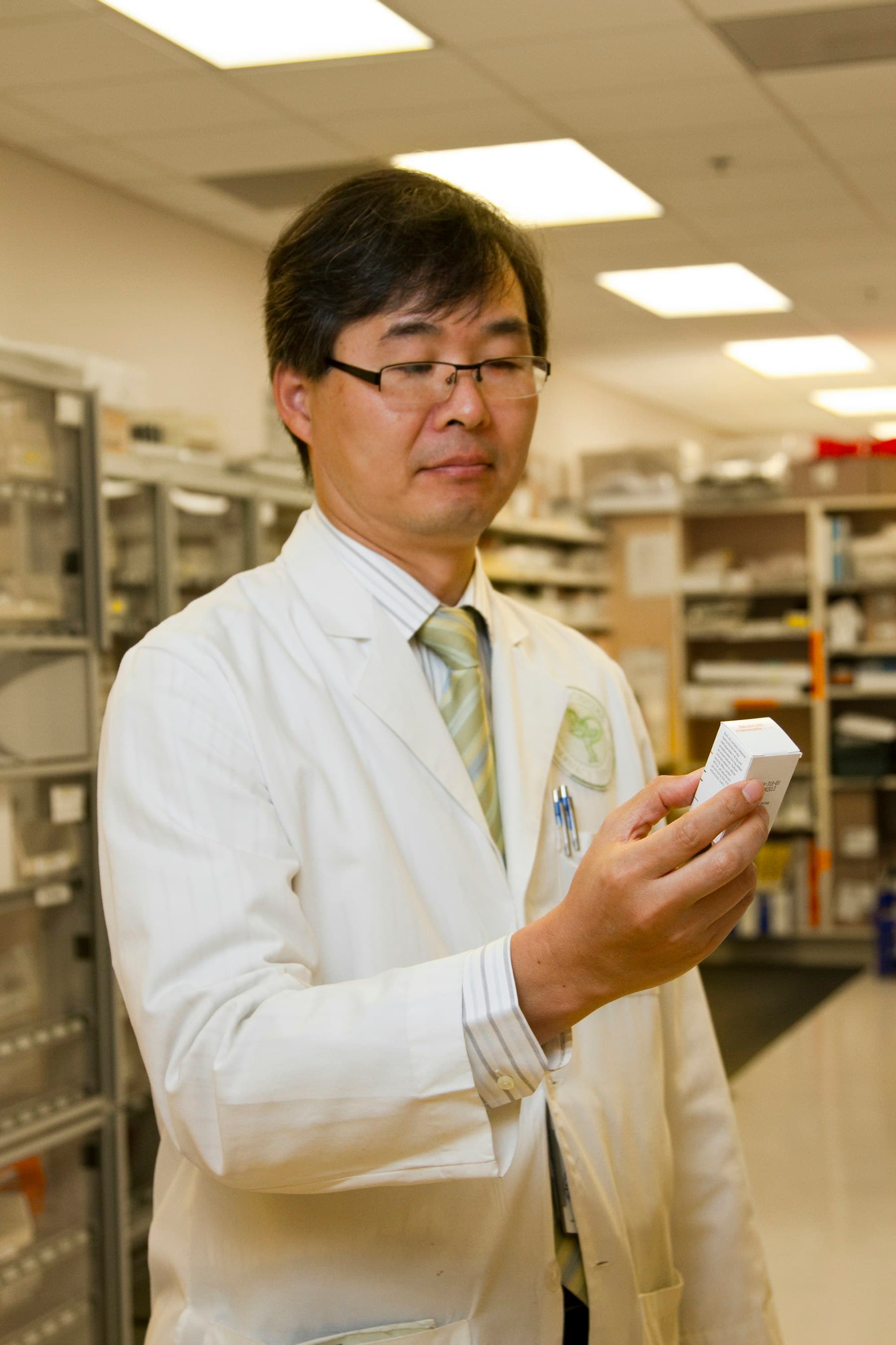 A pharmacist checking a medicine pack against the dispensary shelves